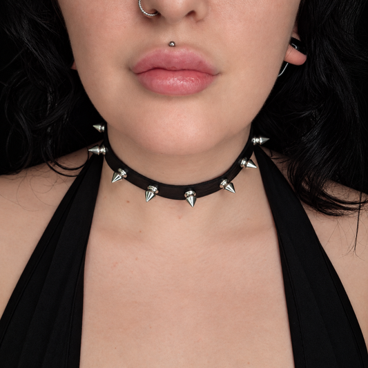 Model wearing the Spiked choker, featuring a black band decorated with evenly spaced silver-tone cone spikes around the neck.
