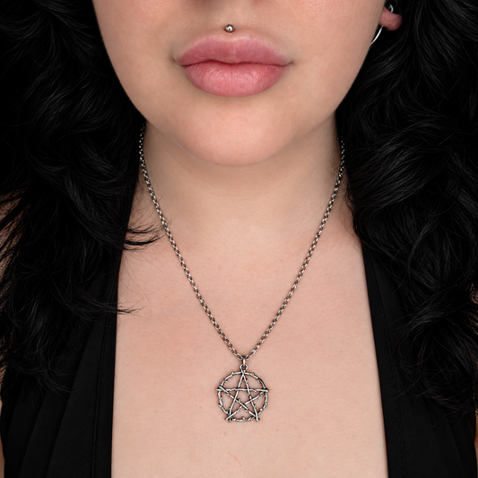 Model wearing the Occults Guard necklace, featuring a silver-tone pentagram pendant formed from intertwined thorn-like branches on a chain.
