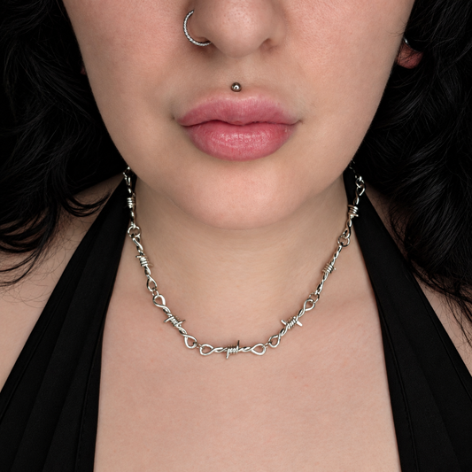 Model wearing the Twisted necklace, featuring a silver-tone chain with alternating oval links and twisted barbed-wire-style detailing around the necklace.