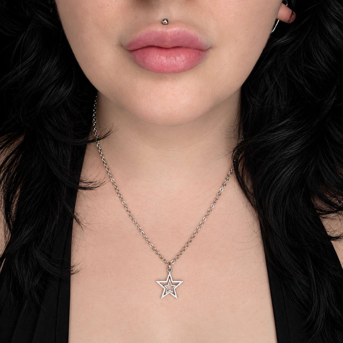 Model wearing the Starstruck necklace, featuring a simple silver-tone outlined five-point star pendant on a delicate chain.